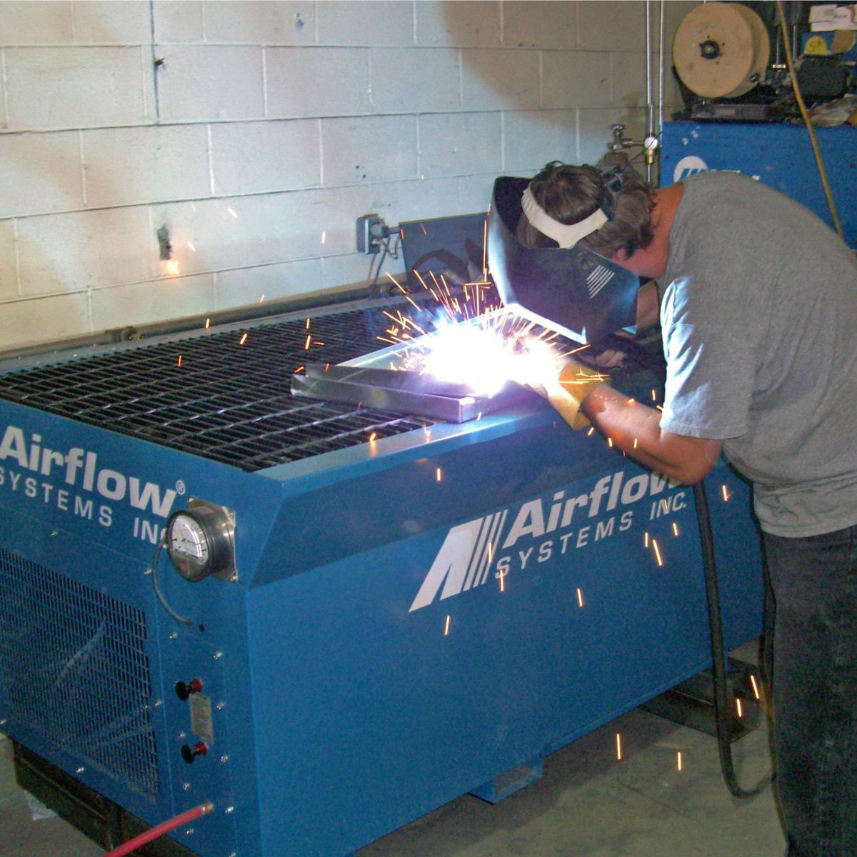 man welding on an Airflow Systems downdraft table